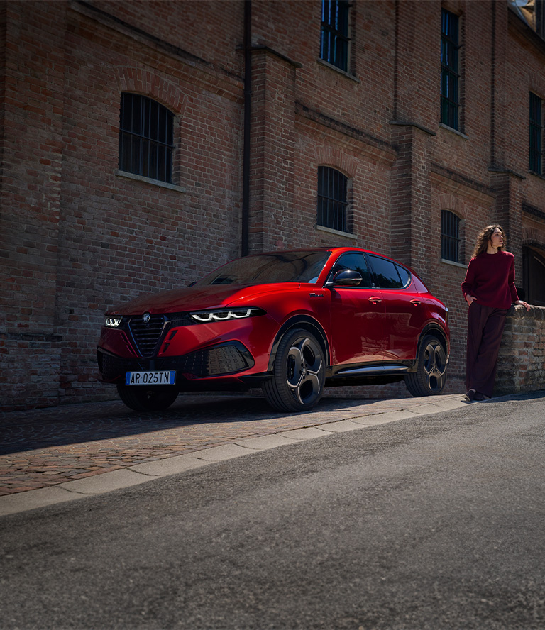 A person in the foreground and a red 2026 Alfa Romeo Tonale in the background, both blurred.