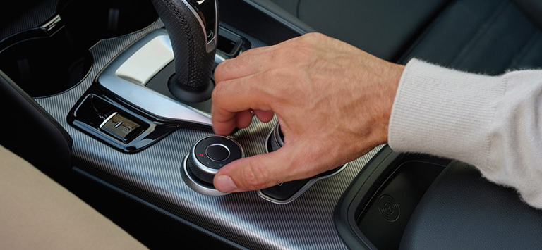 The DNA Drive Mode Selector located in the center console, along with the transmission shifter and the radio controls in the 2026 Alfa Romeo Giulia.