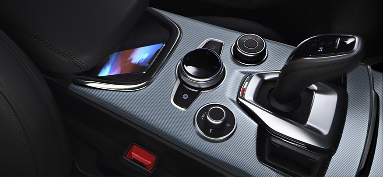 The wireless charging pad located in the center console, along with the radio controls, DNA Drive Mode Selector and transmission shifter in the 2026 Alfa Romeo Stelvio.