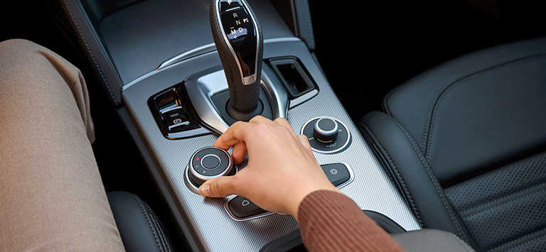 The DNA Drive Mode Selector located in the center console, along with the transmission shifter and the radio controls in the 2026 Alfa Romeo Stelvio.