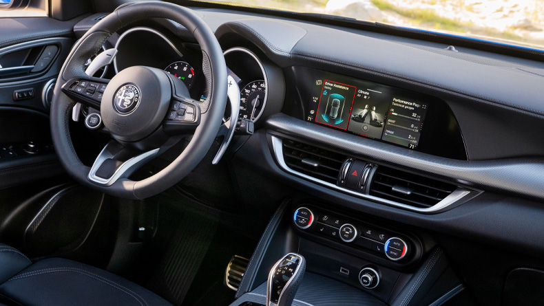 The steering wheel, Uconnect touchscreen, heating and cooling vents and center console controls in a 2026 Alfa Romeo Stelvio.